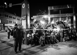 Image of reporters standing behind a police line with an officer in fron