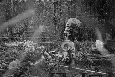 Several abandoned sculptures on the ground surrounded by weeds