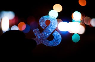 An ampersand stencil held up in front of street lights at night